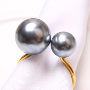 Elegant gold U-shaped napkin ring featuring two grey pearls on a white linen napkin