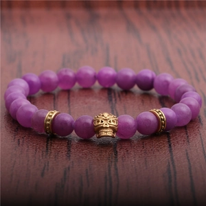 Punk style 8mm purple bead bracelet featuring a gold skull charm on wood background