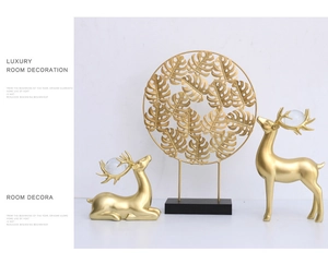 Detailansicht matter goldener Elch-Skulpturen und eines runden Monstera-Metallornaments