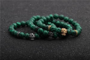 Detailed macro view of 8mm green malachite bead bracelets with skull charms
