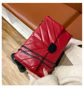 Red chevron quilted shoulder bag with black metal chain strap and geometric lock detail