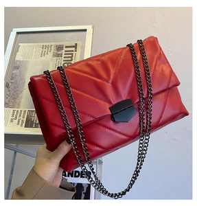Macro shot of red quilted faux leather texture and metal lock on the chain bag