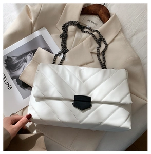 Detail of white quilted crossbody bag with V-stitch pattern and black metal chain