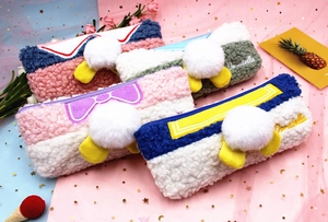 Close-up of plush teddy fleece pencil cases with sailor bows and fuzzy pom-poms