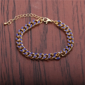 Gold Cuban chain bracelet with purple enamel links on a textured wooden background