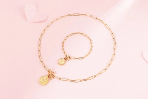 Détail de la parure de bijoux trombone dorée avec pendentif pièce et fermoir en T