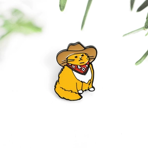 Cute cartoon orange cat enamel pin wearing a western cowboy hat and red scarf on white background