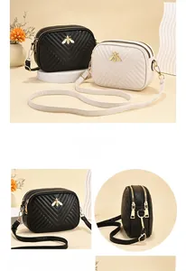 Macro shot of V-shaped quilted leather and gold bee buckle on dual-zipper bags