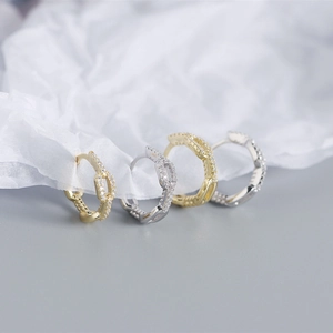 Macro view of gold and silver chain link hoop earrings with sparkling crystal accents