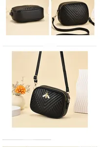 Detail view of black V-quilted leather bag with golden bee emblem and dual zipper structure