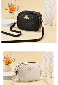 Detail of cross-body bag featuring V-shaped quilting and golden bee metal hardware