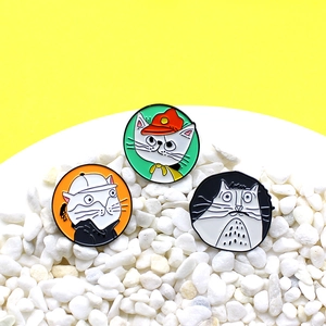 Three-piece set of round enamel cat badges on white stones with yellow background