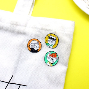 Three colorful cartoon cat enamel pins on white canvas bag with vibrant yellow background