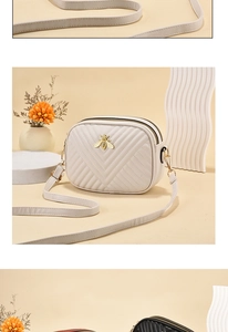 Detail view of cream crossbody bag featuring V-shaped quilting and a gold bee emblem