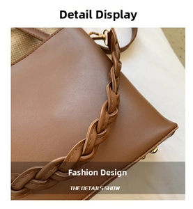 Detail of a brown leather bucket bag featuring a thick braided strap and gold metal buckles