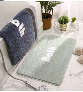 Close-up of soft microfiber absorbent bath mats in mint green, navy, and grey colors