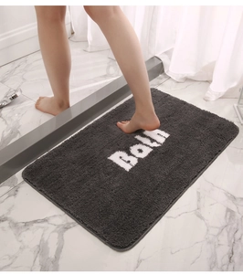 Detail showing plush dark grey non-slip bath mat with white Bath text in bathroom