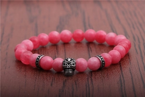 Detailed view of pink agate beads and silver skull charm on a beaded stretch bracelet