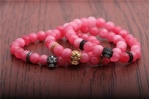 Macro shot of 8mm pink agate beads bracelets with gold, silver and black skull charms