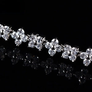 Dettaglio macro di bracciale con fiori di zircone, petali quadrifoglio e castone a griffe