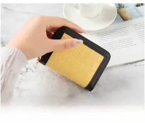Close-up of yellow crocodile texture credit card wallet with black trim and gold zipper