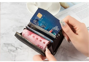Detail of dark brown leather card holder with accordion slots and metal zipper closure