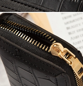 Macro detail of black crocodile pattern leather wallet with high-quality gold metal zipper