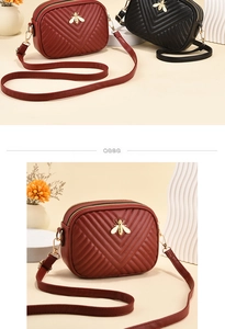 Close-up of quilted camera bag featuring golden bee hardware and dual zipper closure