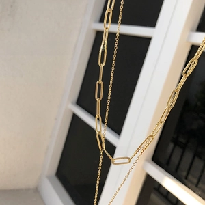 Close-up of gold double-layer necklace with paperclip links and fine circular chain