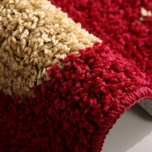 Close-up of red and beige plush entrance mat showing thick fiber texture and durable edges