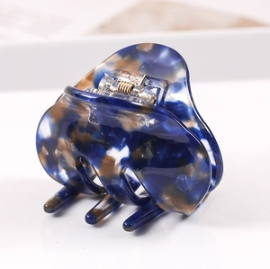 Detailed close-up of blue marble pattern acetate hair claw clip with golden spring