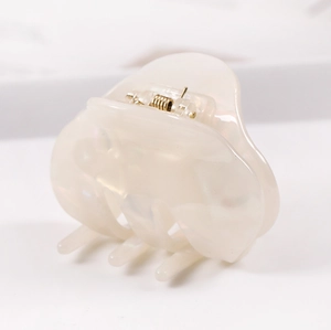 Macro detail of elegant pearlescent acetate hair claw with durable gold metal spring