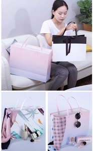 Detailed view of white cardboard gift bags featuring ribbon handles and diverse prints