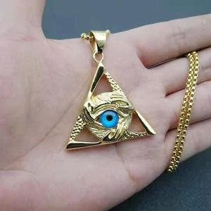 Detailed close-up of a golden triangle evil eye pendant held in hand for men's jewelry