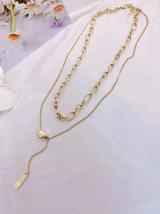 Detail of double-layer gold titanium steel necklace with bean and tag pendants