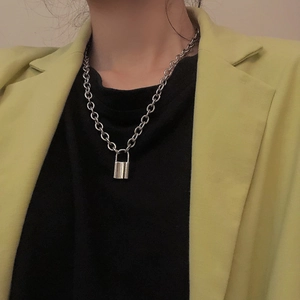 Close-up of a hip hop style silver lock pendant necklace worn on a yellow suit