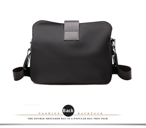 Back view of a black nylon shoulder bag featuring a leather flap closure and fabric strap