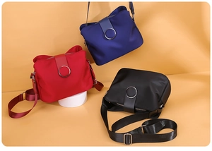 Three mini nylon crossbody bags in navy blue, red, and black with adjustable PU straps