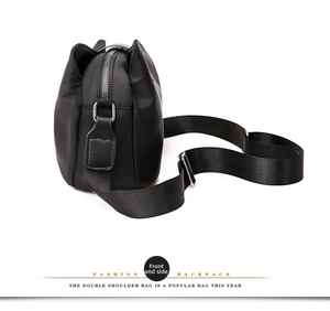 Side view of black mini crossbody phone bag with silver zippers and nylon straps