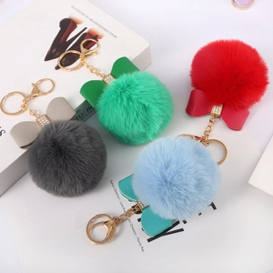 Detail view of 8cm faux rabbit fur pompom keychains with leather bows in four vibrant colors