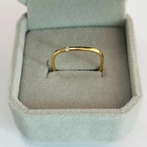 Macro detail of gold square titanium ring with a square-cut zircon in a gray jewelry box