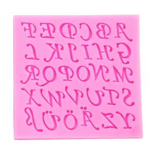 Macro detail of a pink silicone mold showing 26 reversed alphabet letters for fondant