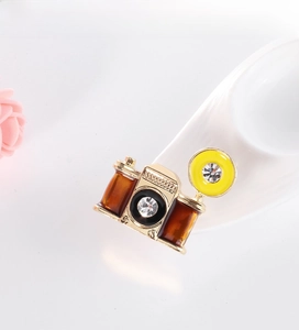 Macro shot of retro camera brooch with gold alloy frame, enamel fill and sparkling rhinestones