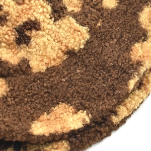 Close-up of thick faux shearling fabric with brown cow print pattern and soft texture