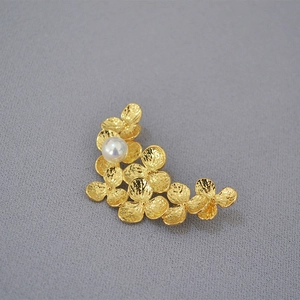 Detail of handcrafted gold leaf brooch with hammered texture and a white pearl accent
