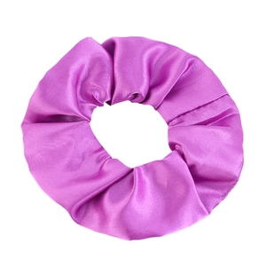 Close-up of a purple satin scrunchie showing the smooth silk-like texture and folds
