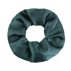 Macro detail of dark green satin scrunchie showing glossy fabric texture and pleats