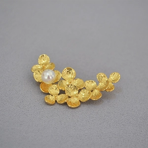 Close-up of gold-plated brass leaf brooch with hammer texture and white pearl
