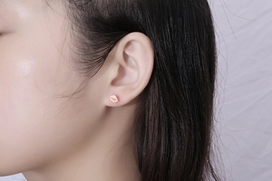Detailed close-up of a mini pink lip-shaped earring with gold accents on the earlobe