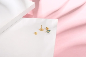 Close-up of golden lip earrings with blue enamel finish on white geometric display stand